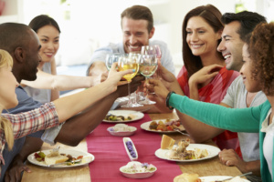 Group Of Friends Making Toast Around Table At Dinner Party